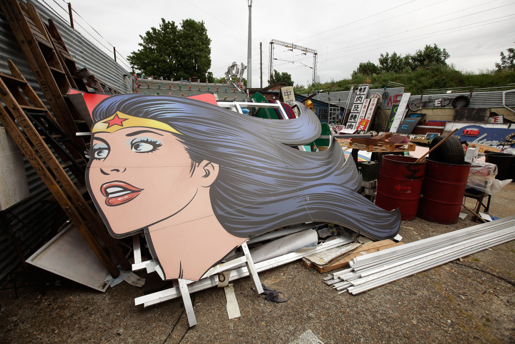 Large painted Wonder Woman face leaning on the ground at an outdoor event.